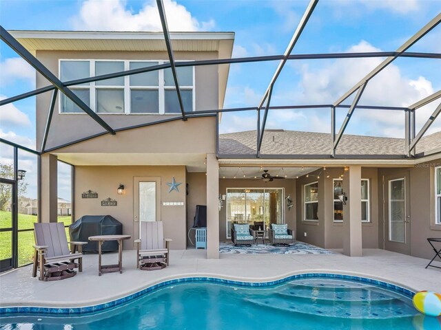 back of house with ceiling fan, a patio area, and glass enclosure