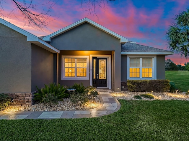 exterior entry at dusk featuring a yard