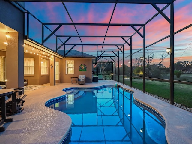 pool at dusk featuring a patio area and a lanai