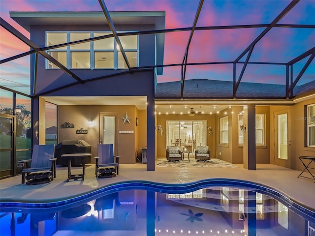 pool at dusk with a patio and glass enclosure