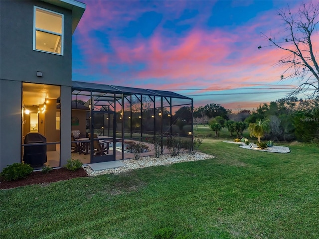 yard at dusk featuring a lanai and a patio area