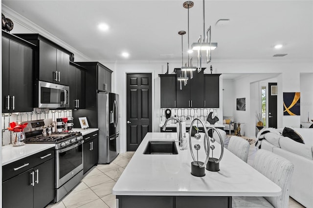 kitchen featuring a kitchen bar, sink, decorative light fixtures, stainless steel appliances, and a kitchen island with sink