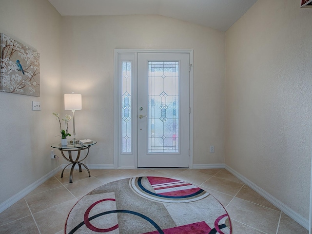 entryway featuring light tile patterned floors and vaulted ceiling