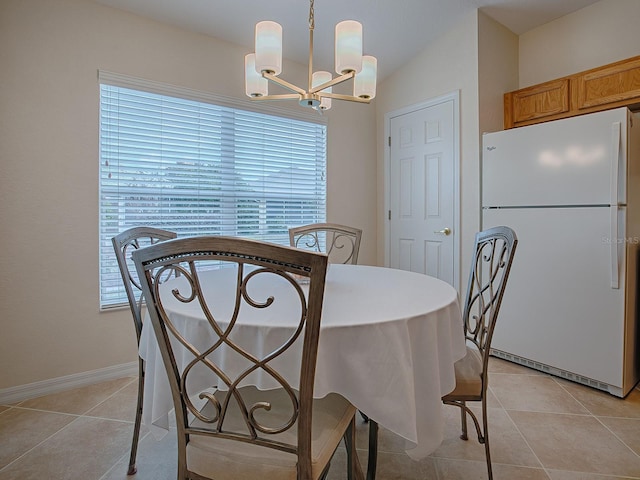 tiled dining room featuring vaulted ceiling, plenty of natural light, and an inviting chandelier