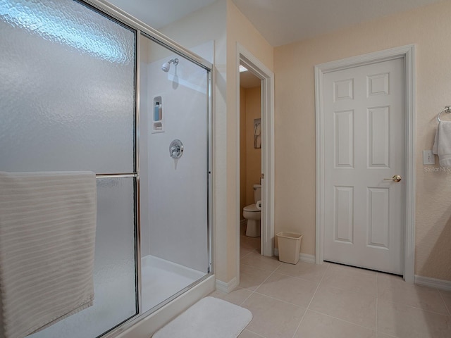 bathroom with a shower with shower door, tile patterned floors, and toilet