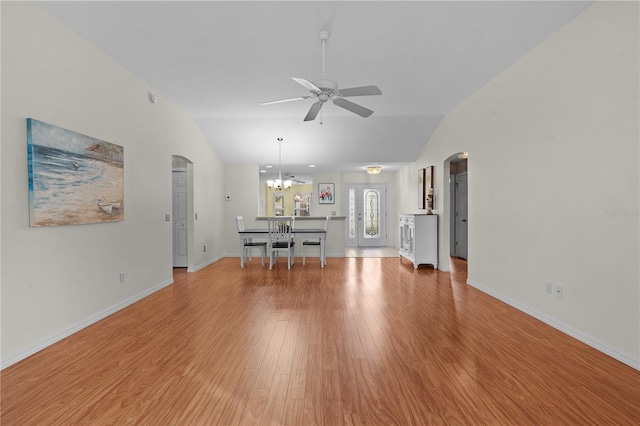 unfurnished living room featuring ceiling fan with notable chandelier, light hardwood / wood-style flooring, and vaulted ceiling