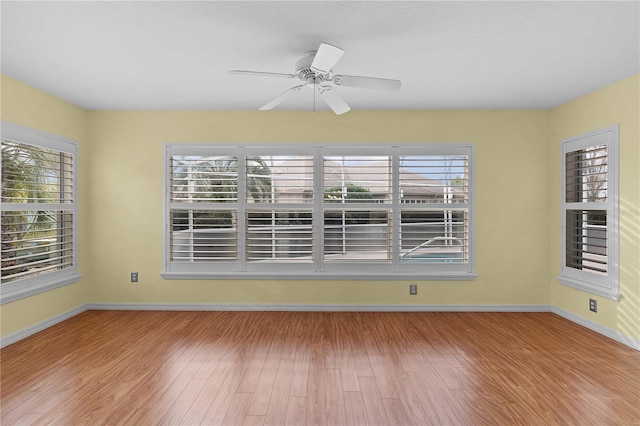 spare room with ceiling fan, plenty of natural light, and hardwood / wood-style floors