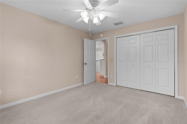 unfurnished bedroom with light carpet, a closet, and ceiling fan