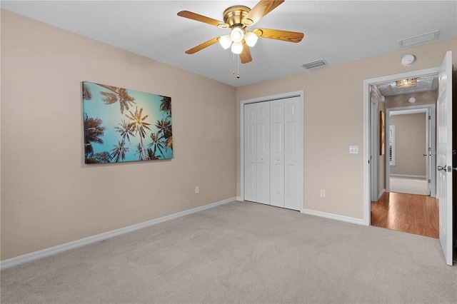 unfurnished bedroom with ceiling fan, light colored carpet, and a closet