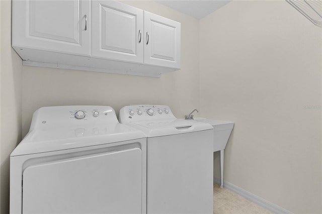 clothes washing area with cabinets and washing machine and dryer