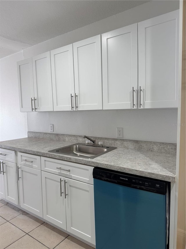 kitchen with light tile patterned flooring, stainless steel dishwasher, sink, and white cabinets