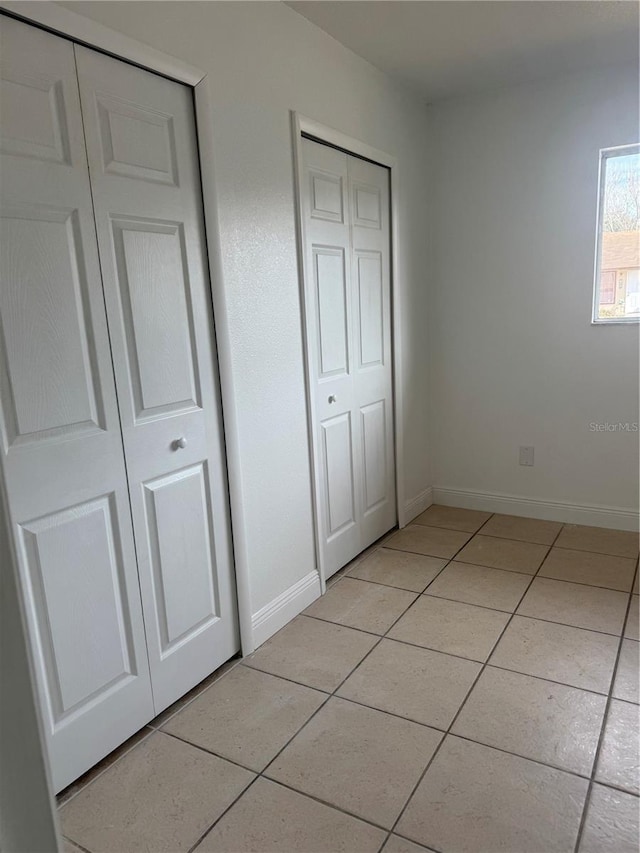 unfurnished bedroom featuring two closets and light tile patterned floors