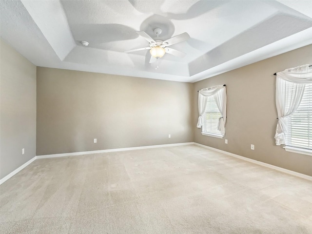 carpeted empty room featuring ceiling fan, a textured ceiling, and a tray ceiling