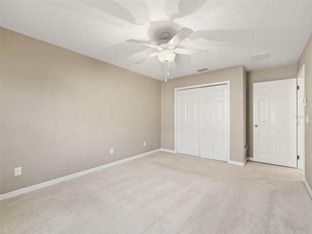 unfurnished bedroom featuring ceiling fan, a closet, and light carpet