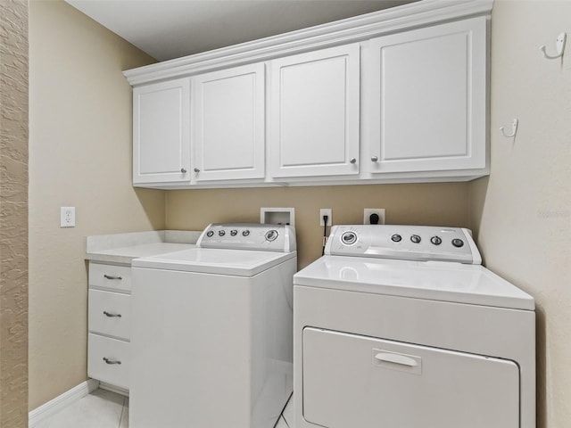 laundry area with washer and clothes dryer, light tile patterned flooring, and cabinets