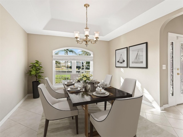 tiled dining area featuring a tray ceiling and a chandelier