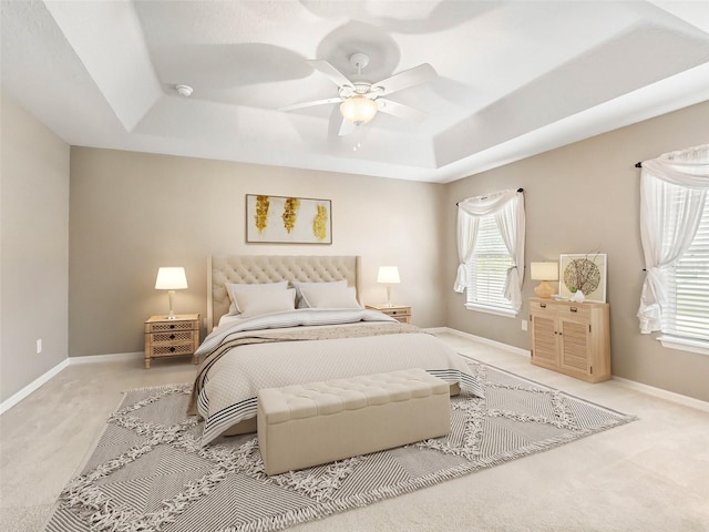 bedroom with a raised ceiling, ceiling fan, and carpet flooring