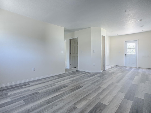 spare room featuring light wood-type flooring and a textured ceiling