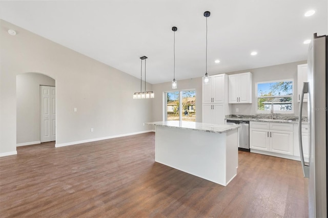 kitchen with white cabinetry, stainless steel appliances, hanging light fixtures, light stone counters, and a center island