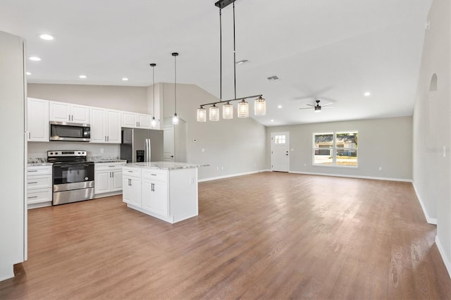 kitchen with ceiling fan, a kitchen island, pendant lighting, appliances with stainless steel finishes, and white cabinets