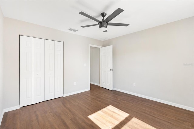 unfurnished bedroom featuring ceiling fan, a closet, and dark wood-type flooring