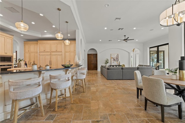 kitchen with a kitchen bar, pendant lighting, stainless steel appliances, and light brown cabinetry