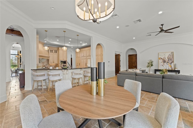 dining room featuring a raised ceiling, crown molding, and ceiling fan with notable chandelier