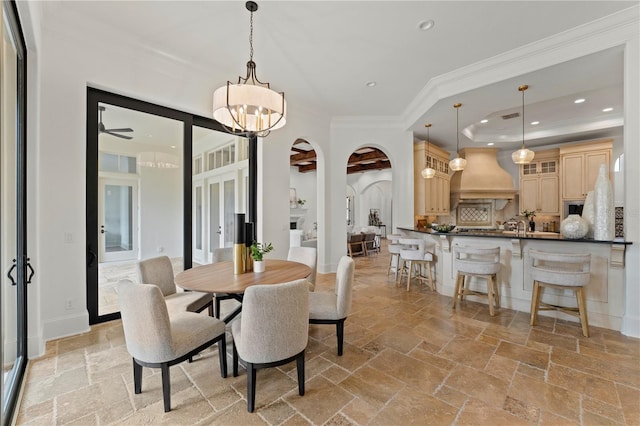 dining space with ceiling fan with notable chandelier, a tray ceiling, and ornamental molding