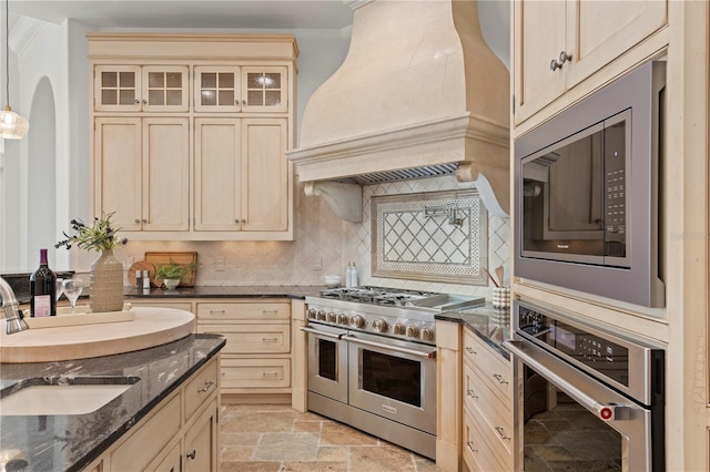 kitchen with sink, premium range hood, pendant lighting, stainless steel appliances, and tasteful backsplash