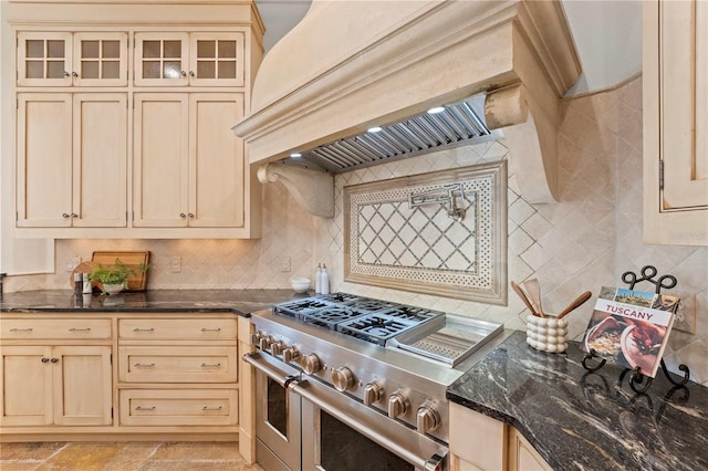 kitchen with decorative backsplash, range with two ovens, custom range hood, and dark stone counters