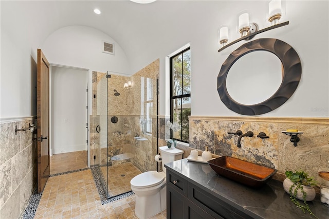 bathroom featuring toilet, a shower with shower door, lofted ceiling, tile walls, and vanity