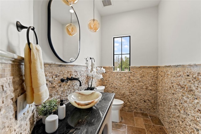 bathroom with tile walls, toilet, and vanity