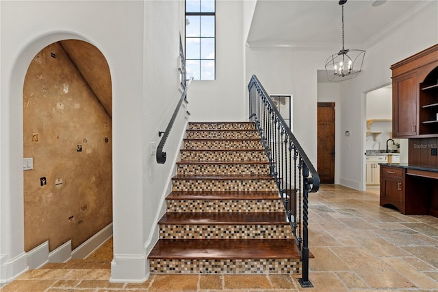 staircase featuring ornamental molding and a chandelier