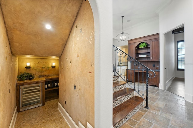 wine area featuring wine cooler, an inviting chandelier, and ornamental molding