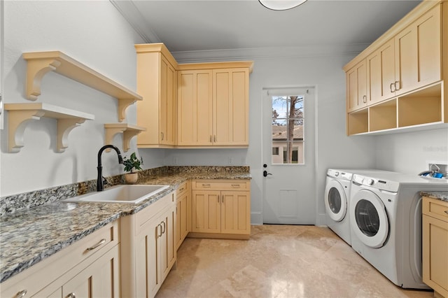 clothes washing area featuring sink, cabinets, crown molding, and washing machine and clothes dryer