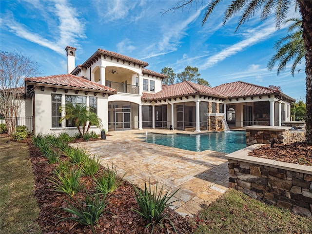 rear view of house with pool water feature, ceiling fan, a patio, a balcony, and a sunroom