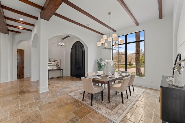 dining space featuring a notable chandelier, beam ceiling, and a high ceiling