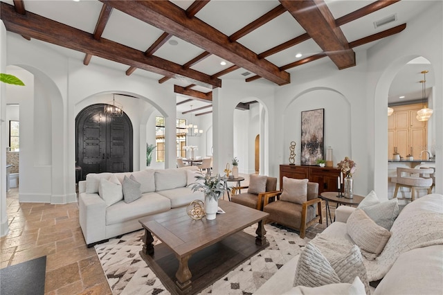 living room featuring a wealth of natural light, a notable chandelier, and beam ceiling