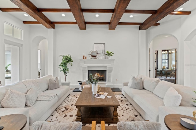 living room featuring coffered ceiling, a chandelier, and beamed ceiling