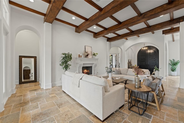 living room with beamed ceiling, a towering ceiling, and coffered ceiling