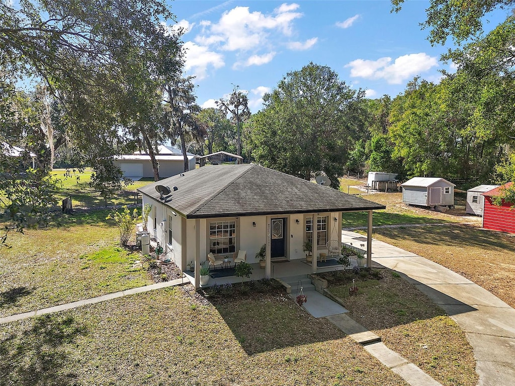 view of front of property featuring a storage unit, covered porch, and a front lawn