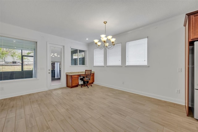 unfurnished office with built in desk, an inviting chandelier, light wood-type flooring, and a textured ceiling