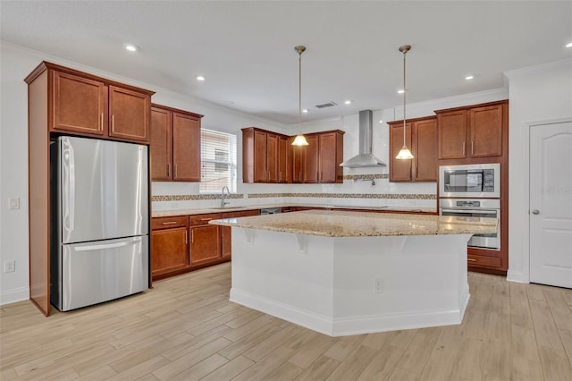 kitchen with wall chimney exhaust hood, pendant lighting, a center island, appliances with stainless steel finishes, and sink