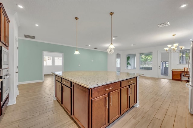 kitchen with light stone counters, hanging light fixtures, a center island, a notable chandelier, and crown molding