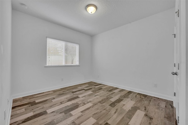 unfurnished room with a textured ceiling and light wood-type flooring