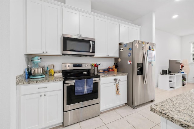 kitchen with light stone countertops, white cabinetry, appliances with stainless steel finishes, and light tile patterned flooring