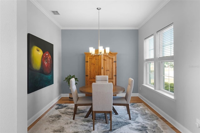 dining area featuring crown molding, wood-type flooring, and a notable chandelier