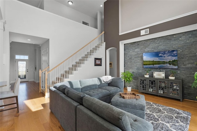 living room with hardwood / wood-style floors and a towering ceiling