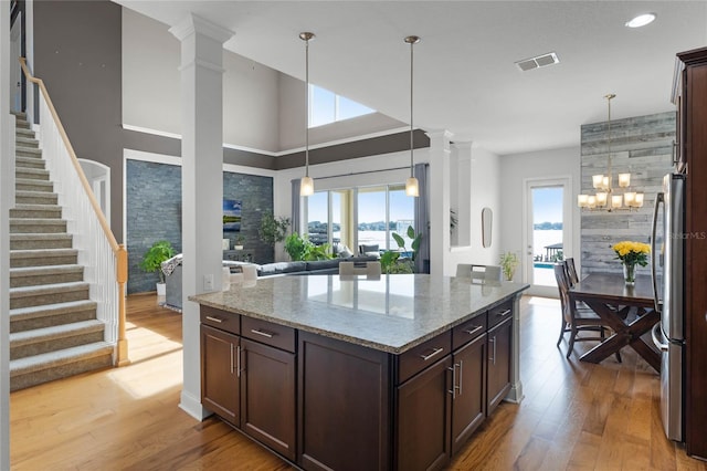 kitchen featuring light stone counters, light hardwood / wood-style flooring, dark brown cabinetry, and stainless steel refrigerator