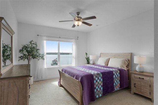 carpeted bedroom with a water view and ceiling fan